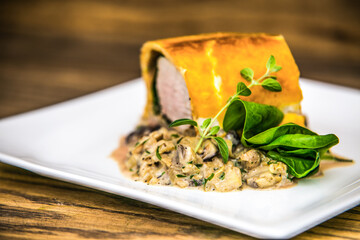 Delicious roast pork fillet with mushroom sauce on a white plate. The food in the restaurant. Food styling and restaurant meal serving.