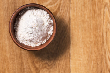 Bread flour in a bowl on a wooden table top view.