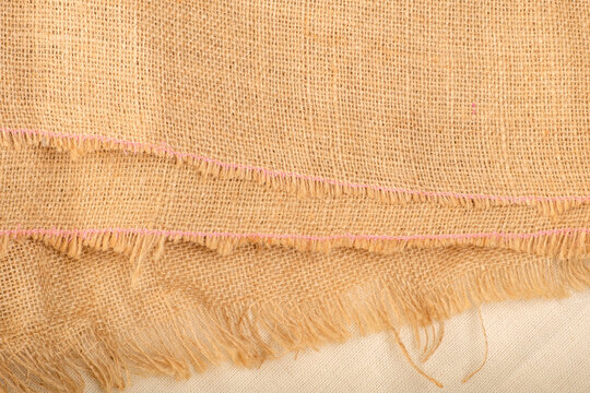 the edges of the linen fabric are stacked on top of each other, with separate threads sticking out from the edges