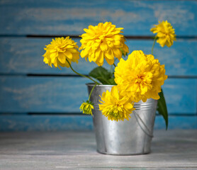 Bouquet of yellow flowers, golden ball with a metal bucket on a wooden table, close-up