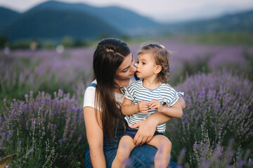 Portrait of attractive young mom with little daughter in lavender summer field. Happy family in...