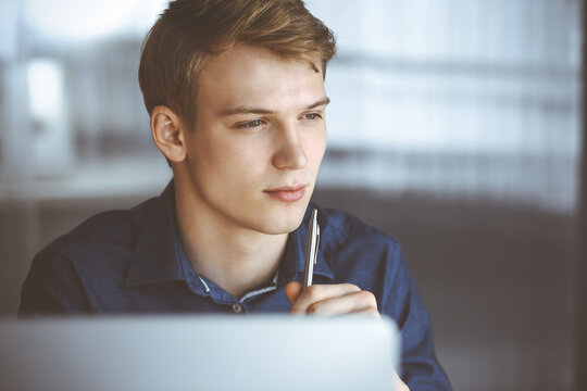 Young Blond Businessman Thinking About Strategy At His Working Place With Computer. Startup Business Means Working Hard And Out Of Time For Success Achievement