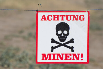 The inscription "Attention! Mines" in German on a white plate. Danger to human health and life.
