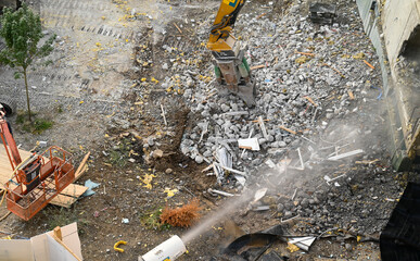  modern building demolition with demolition pliers and irrigation against the dust