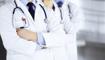 Group of modern doctors standing as a team with crossed arms and stethoscopes in hospital office. Physicians ready to examine and help patients. Medical help, insurance in health care, best desease