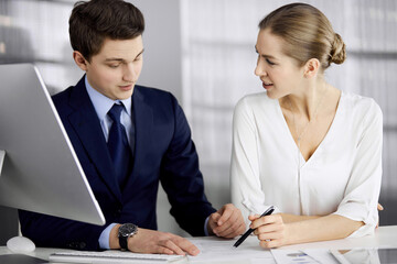 Business people discussing something while sitting in office. Focus at businesswoman while talking to her male colleague. Teamwork and meeting concept