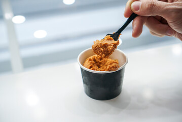 Thai Tea ice cream. People scooping Thai tea ice cream in black paper cup with white background.
