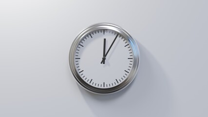 Glossy chrome clock on a white wall at five past twelve. Time is 00:05 or 12:05