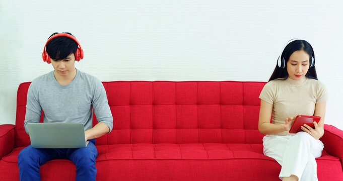 Asian Woman And Man Sit On Tablet And Laptop Headphone While Sitting In A Meeting Room Social Distancing. Using Common Area With A Distance Between People To Prevent Coronavirus Infection