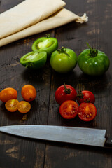 still life with fresh red, green and yellow tomatoes freshly picked from the garden on the wooden table and knife