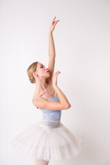 Fototapeta premium beautiful young blonde woman ballerina training calilisthenics exercise on white studio background.