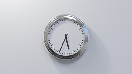Glossy chrome clock on a white wall at thirty-four past five. Time is 05:34 or 17:34