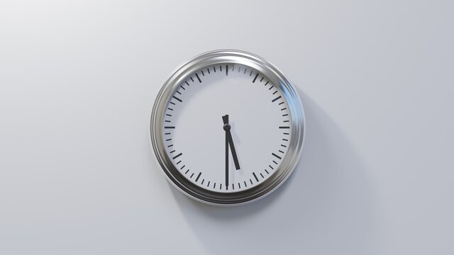 Glossy chrome clock on a white wall at half past five. Time is 05:30 or 17:30