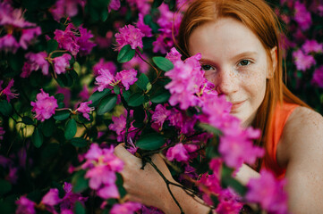 Naklejka premium Portrait of attractive young girl in a summer dress enjoys of the purple plants in the botanical garden