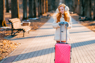 Beautiful cute girl with red hair is afraid to freeze in the autumn, so dressed very warmly and went for a walk