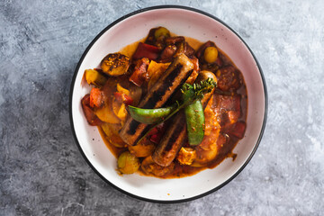 plant-based food, tomato potato and snowpeas roast with vegan sausages