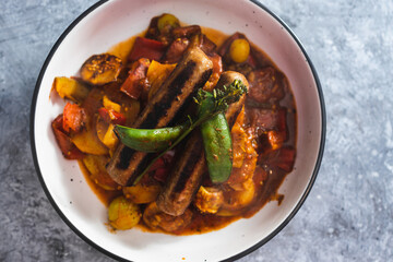 plant-based food, tomato potato and snowpeas roast with vegan sausages