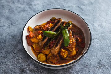 plant-based food, tomato potato and snowpeas roast with vegan sausages