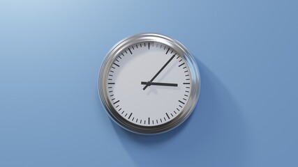 Glossy chrome clock on a blue wall at seven past three. Time is 03:07 or 15:07