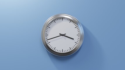 Glossy chrome clock on a blue wall at forty-two past three. Time is 03:42 or 15:42