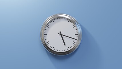 Glossy chrome clock on a blue wall at eighteen past five. Time is 05:18 or 17:18
