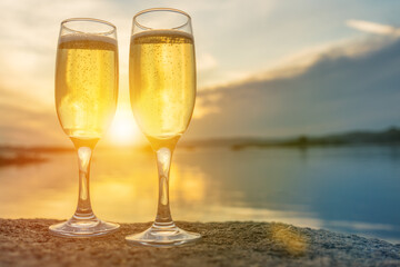 Two glasses with champagne on the background of the sunset, in nature, outdoors. Ramontic evening for lovers