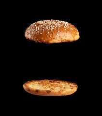 baked sesame seed round bun cut in half, halves fried and levitating in air over each other