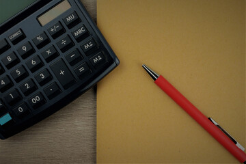 Workplace, wooden table on top, notebook, red pen and calculator