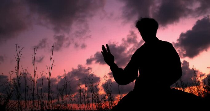 Silhouette of a man doing Chi Kung during a sunset. Concept: martials arts