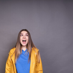 A happy curious excited woman is looking up, with a joyful expression on her face.