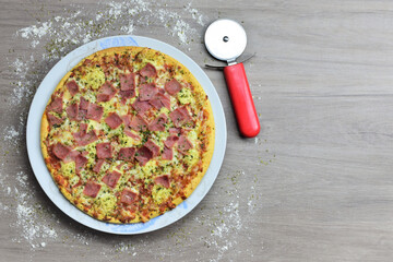 Pizza with cheese and sweet ham, dough cutter on wooden table, space for text
