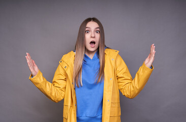 Astonished beautiful female wearing yellow anorak demonstrating size of something big.