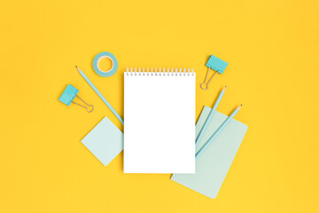 Notepad template with mint stationery on a bright yellow background. Creative mockup with copy space.