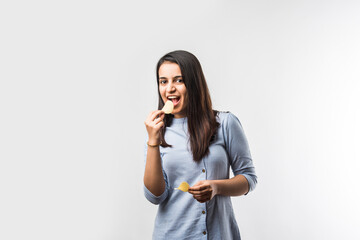Indian / asian pretty young girl eating potato chips on white background with copyspace