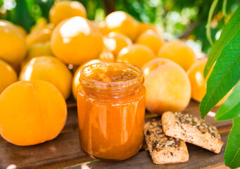 still life of ripe appetizing yellow peaches and marmalade on table in garden