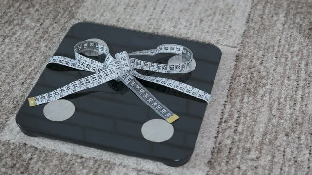 To control body fat. The scales are tied with a bow made of a centimeter tape.