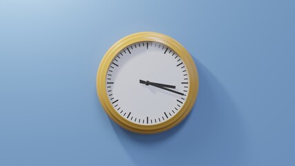Glossy orange clock on a blue wall at eighteen past three. Time is 03:18 or 15:18