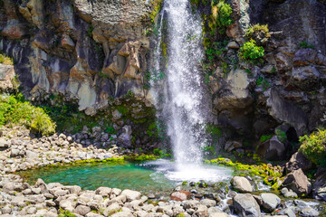 Obraz premium A small pool underneath Taranaki falls surrounded by rocks