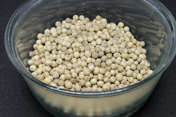 White pepper grains isolated on black background