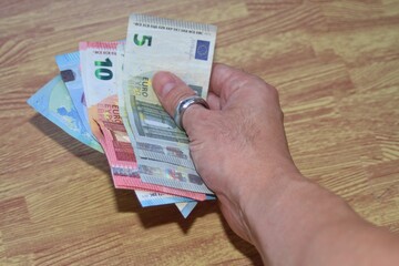 Mano con dinero en tiempos de crisis económica