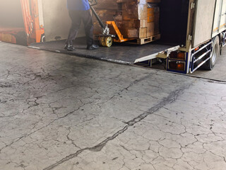 Worker driving forklift loading and unloading shipment carton boxes and goods on wooden pallet from container truck to warehouse cargo storage in logistics and transportation industrial 