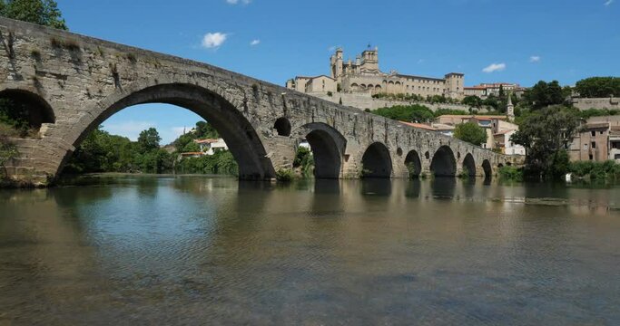 Beziers, Herault, Occitanie, France. In the foreground, the old bridge over crossing  the Orb river. In the background is the cathedral Saint Nazaire 