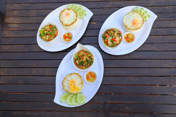 Pad Ka-prao; stir fried chopped chicken with chili and basil, served with steamed rice and fried egg on top set on wooden table
