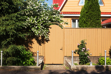 Wooden gate to the country house . Summer day, trees blossom. House is well maintained and accurate