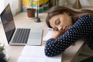 Tired millennial female student fall asleep on desk studying preparing for exam or test, exhausted...