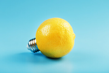 Lemon light bulb on a blue background. The fruit of a lemon with base from the bulb E27.
