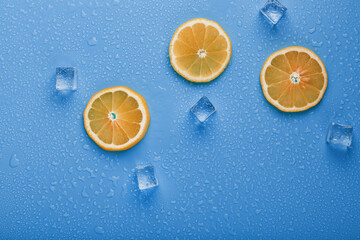 Slices of fresh orange on a blue background with ice.