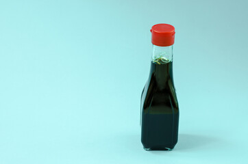 Glass bottle with soy sauce on a blue background close-up. Ingredient for cooking.