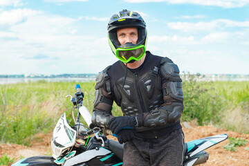 A man in motorcycle equipment sits on an enduro motorcycle.