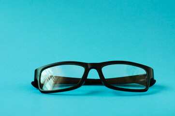 Glasses in black plastic frames on a blue background. Close-up glasses with place for your text.